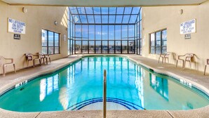 An indoor swimming pool with clear glass walls, chairs around the pool, and signs indicating no lifeguard on duty. - Views & Indoor Pool - San A Bel 315 (North Myrtle Beach)