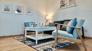 A cozy living room with a white coffee table, a blue sofa, and a patterned rug. - Vacation home Wolthuser Warf 3 - emden and sea - idyllic living for 4 close to the city (Emden)
