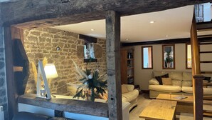 Una sala de estar acogedora con pared de piedra, techo de madera, sofá de cuero, mesa de centro de madera y sofá color beige.