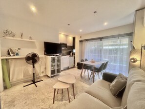 A modern living room with a sofa, a dining table, and a kitchen area with a TV. - Jolies Lavandes (Cannes)