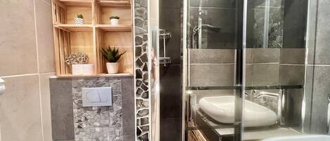 Ein modernes Badezimmer mit einer gläsernen Duschkabine, einer weißen Badewanne und einem Waschtisch.