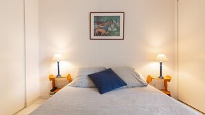 Ein Schlafzimmer mit einem Bett, zwei Nachttischlampen, einem Bild an der Wand und einem kleinen Tisch mit Lampe.