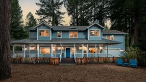A two-story house with a porch, a blue door, and a wooden fence.