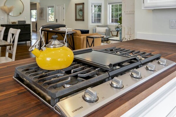 A kitchen with a modern gas stove and a yellow kettle on the countertop.
