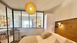 Une chambre moderne avec un grand lit, une tête de lit en bois et un luminaire suspendu.