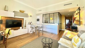 Un salon moderne doté d’un téléviseur à écran plat, d’un canapé et d’un coin repas avec des chaises et une table.