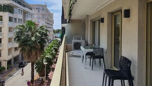 A balcony with a table and chairs, a palm tree, and a view of the street and buildings. - Branly 4, 1 bedroom 50 meters from Croisette parking in etra (Cannes)