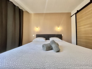 Ett hotellrum med en stor säng, två väggmonterade lampor och en sänggavel.