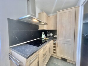 A compact kitchen with a black marble backsplash, stainless steel appliances, and light wood cabinetry. - Carre d'or duplex (Cannes)