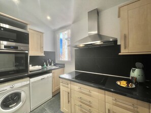 A modern kitchen with stainless steel appliances, a dishwasher, and a built-in oven. - Carre d'or duplex (Cannes)