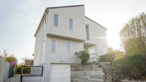 Kaksikerroksinen talo, jossa on autotalli, pieni etupiha, jossa on muutama porras, ja aita.