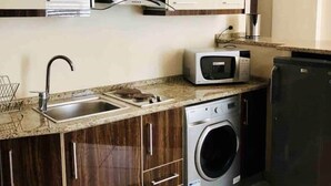 Una cocina compacta con lavadora integrada, microondas y lavabo.