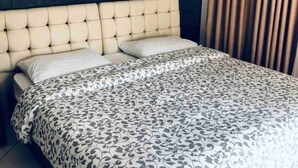 Una cama con cabecera capitonada, ropa de cama estampada y una pared oscura con diseño geométrico.