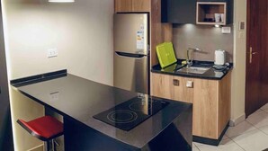 Een moderne keuken met een centraal eiland, een ingebouwde kookplaat, een koelkast en houten kastjes.