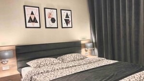 Een hotelkamer met een bed, een nachtkastje, een lamp en drie ingelijste kunstwerken aan de muur.
