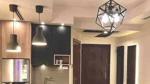 Een moderne keuken met een centraal eiland, roestvrijstalen apparatuur, hangende lampen en een plafondventilator.