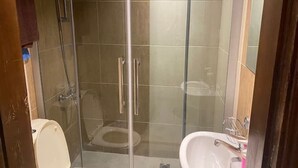 A bathroom with a glass-enclosed shower, a toilet, and a sink.