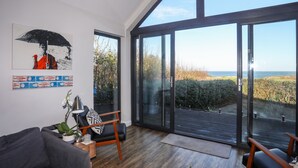 A modern living room with a large sliding glass door leading to a balcony with a view of the sea.