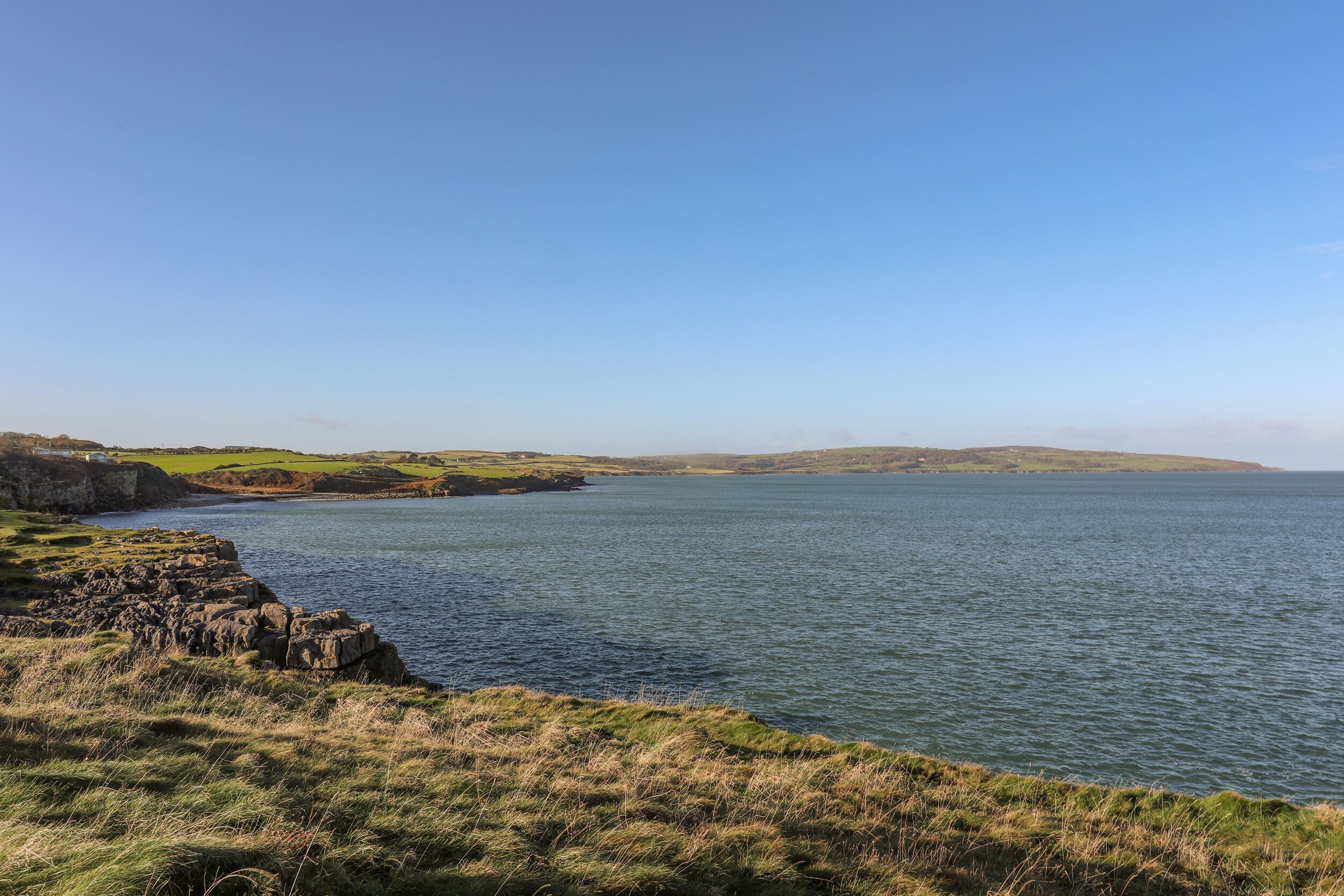 Un paysage côtier avec une rive rocheuse et une mer calme.