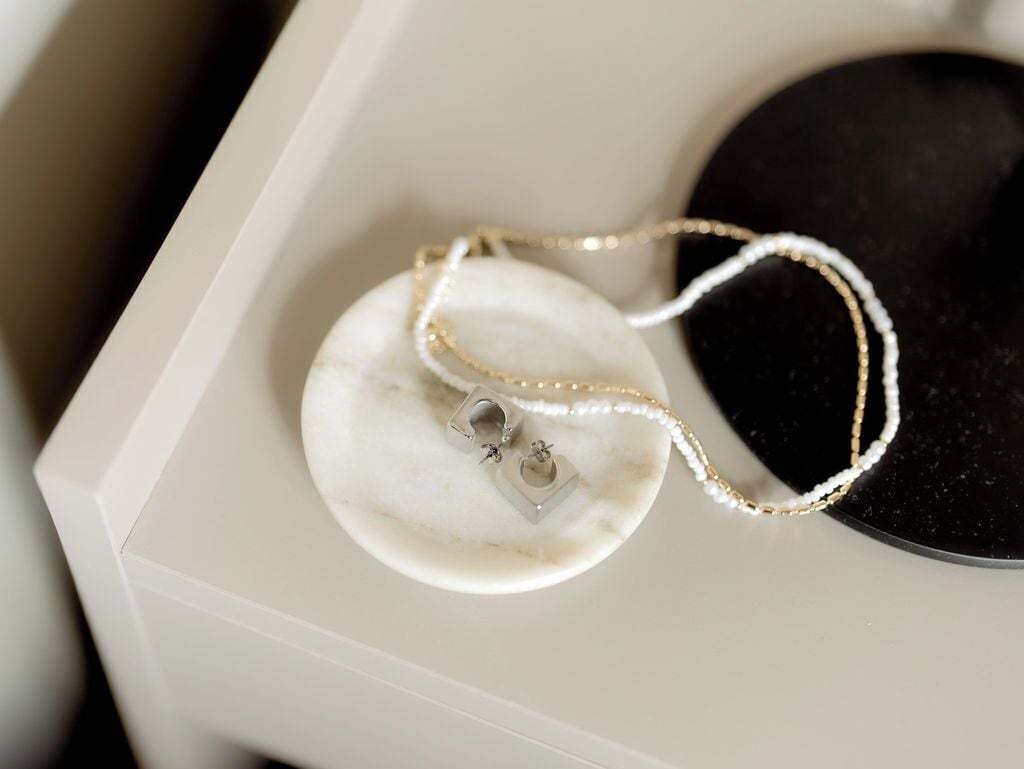 Un présentoir à bijoux avec un collier posé sur une surface en marbre.