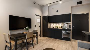 A modern kitchen with black cabinets, a built-in oven, and a dining area with a table and chairs.