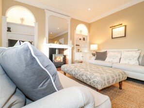 A cozy living room with a sofa, ottoman, and a fireplace.