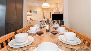 Un espace repas avec une longue table en bois dressée pour un repas, entourée de chaises.