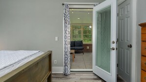 Ein Schlafzimmer mit einem Bett, einer Tür, die auf einen Balkon führt, und Blick ins Freie.