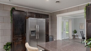Eine moderne Küche mit dunklen Holzschränken, einem Edelstahlkühlschrank und einer Granitarbeitsplatte.