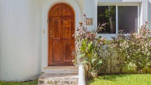 A house with a wooden front door, a stone staircase, and a number '76' sign on the wall. - Playacar Townhome: Pool, Patio & Beach Walk (Playa del Carmen)