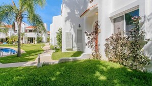 A white building with a pool, palm trees, and a well-maintained lawn. - Playacar Townhome: Pool, Patio & Beach Walk (Playa del Carmen)