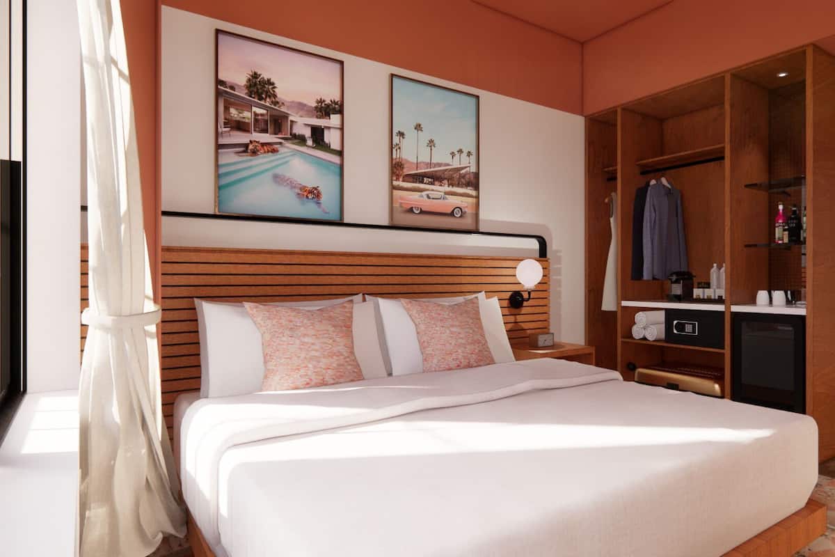 A bedroom with a bed, a wooden headboard, a wardrobe, and two framed pictures on the wall.