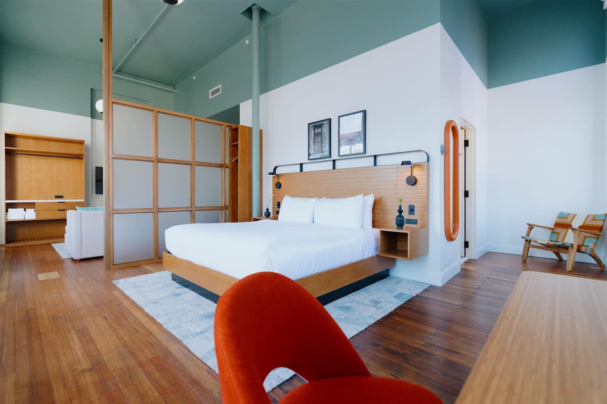 A modern bedroom with a large bed, wooden furniture, and a view of the outdoors.