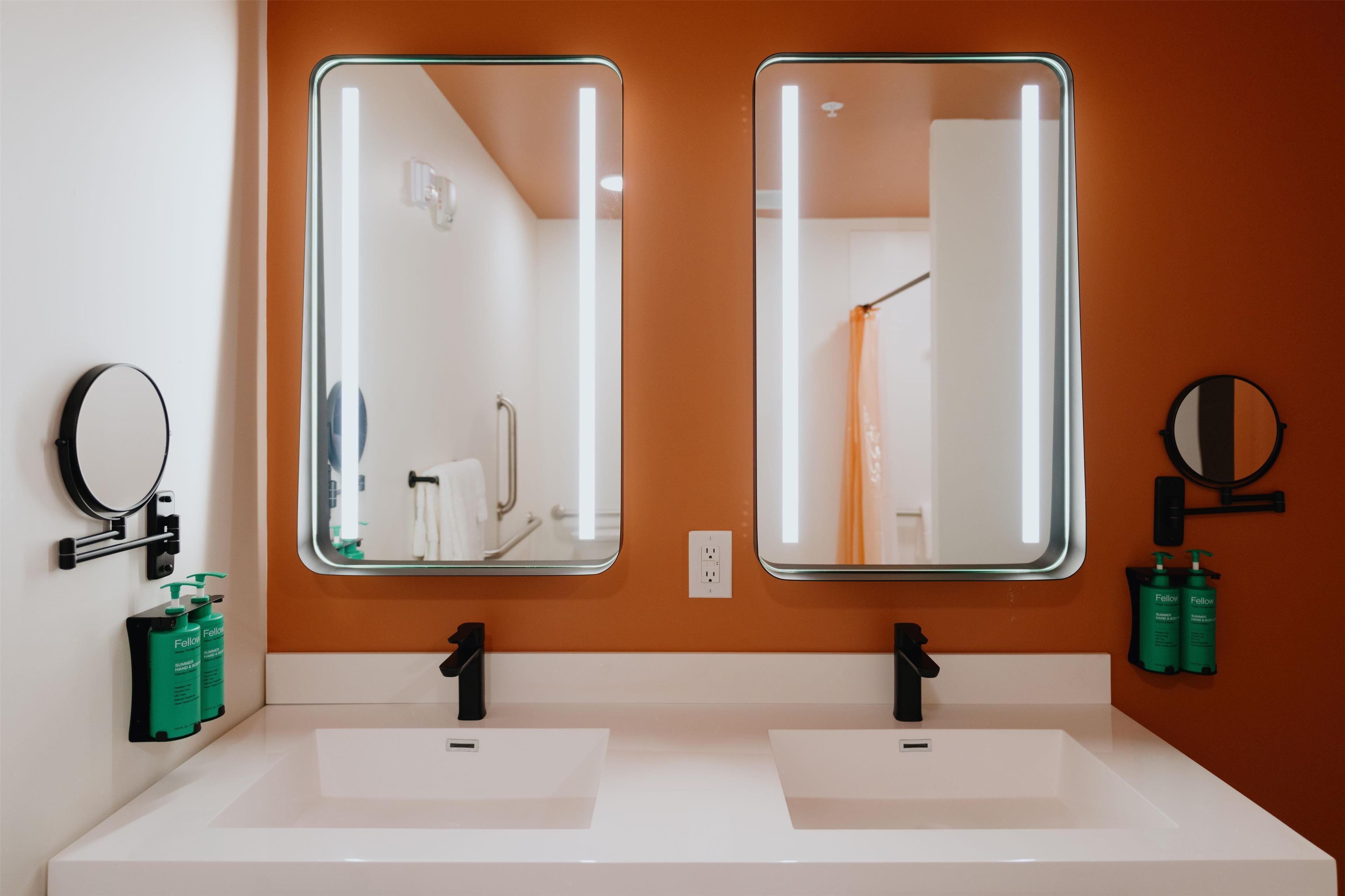Une salle de bain avec deux lavabos, un miroir rond et deux miroirs rectangulaires.