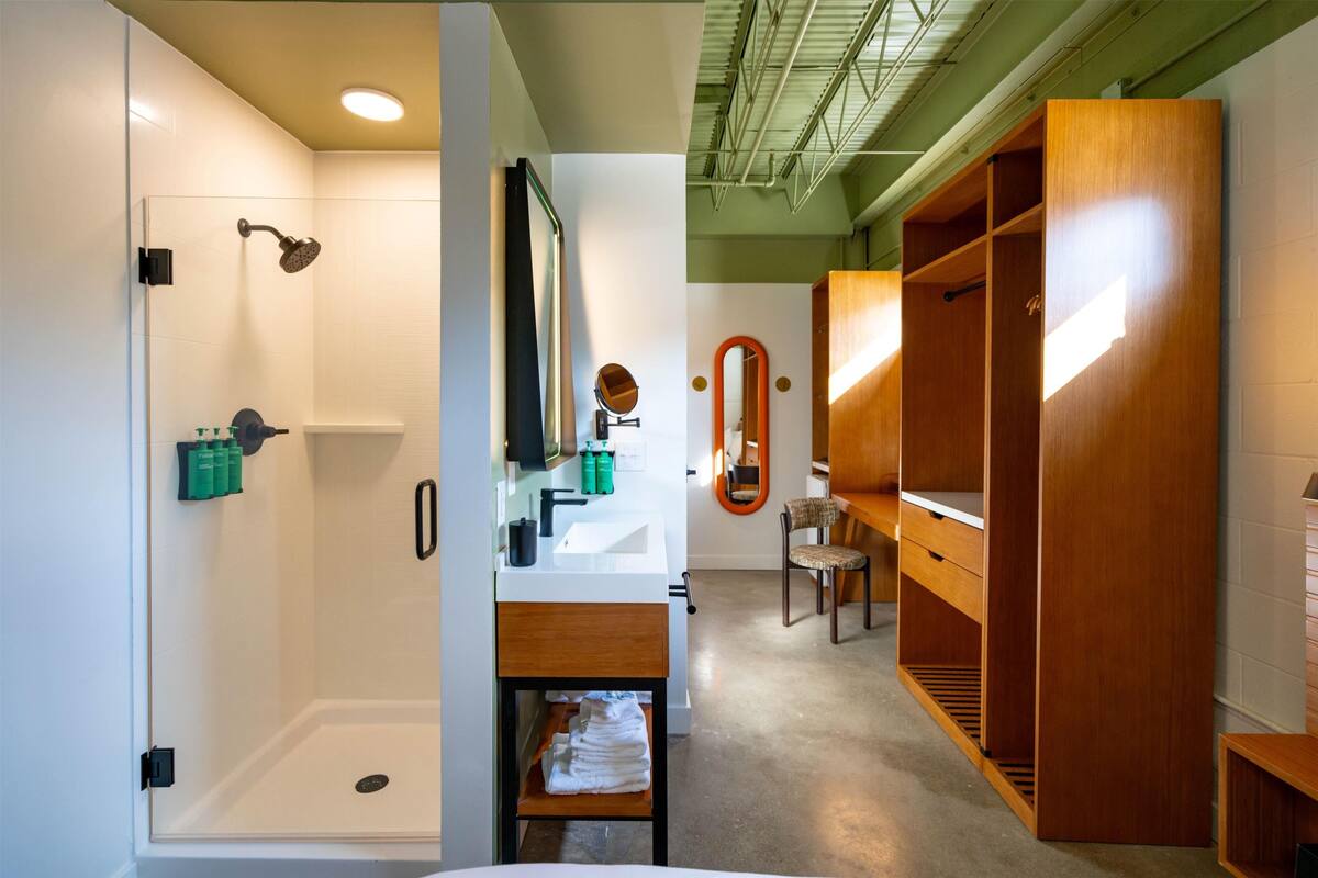 A modern bathroom with a shower, sink, and wooden storage.
