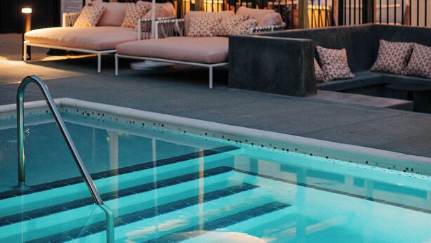 A pool area with lounge chairs and a covered seating area.