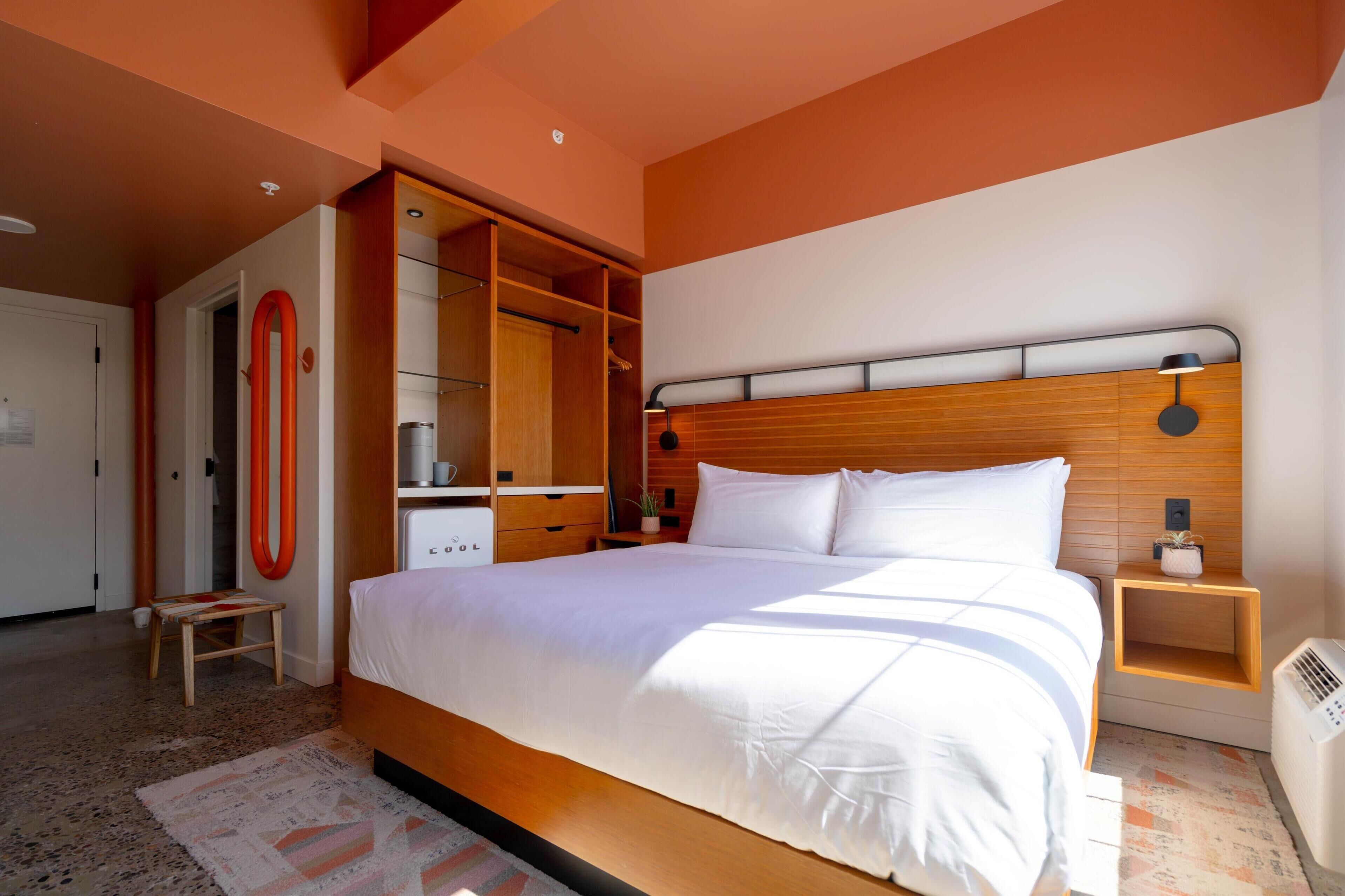 A modern bedroom with a large bed, wooden headboard, built-in wardrobe, and bedside tables.