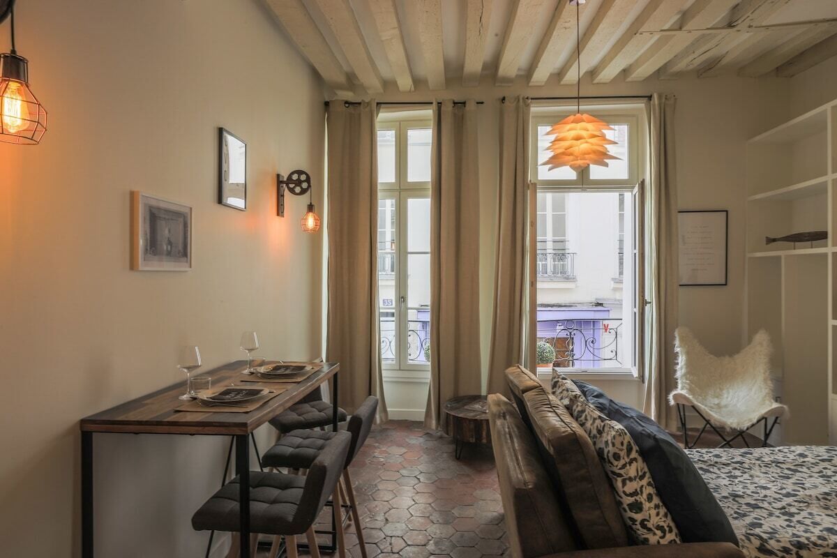 Une pièce chaleureuse avec une table à manger en bois, des bancs, un canapé et une chaise blanche.