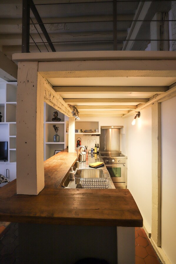 Una cocina con encimera de madera, electrodomésticos de acero inoxidable y salpicadero de azulejos.