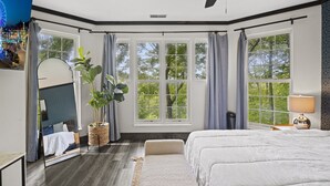 Un dormitorio con una cama grande, una planta en maceta, un espejo y una ventana con cortinas.