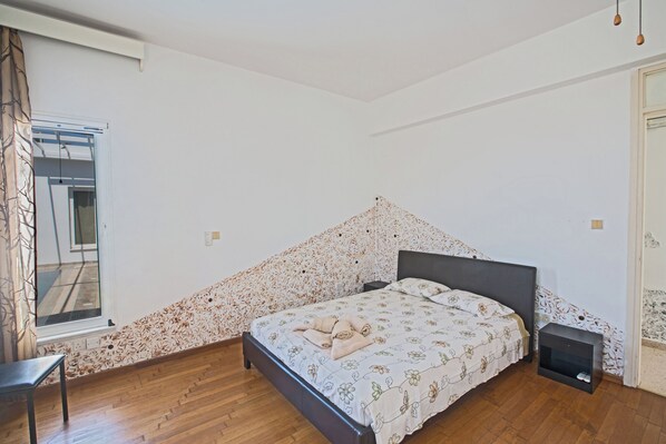 A bedroom with a bed, a nightstand, a chair, and a window.