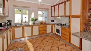 Cocina con gabinetes de madera, microondas, estufa y pileta.
