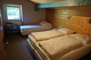 A room with two beds, a chair, and a window.