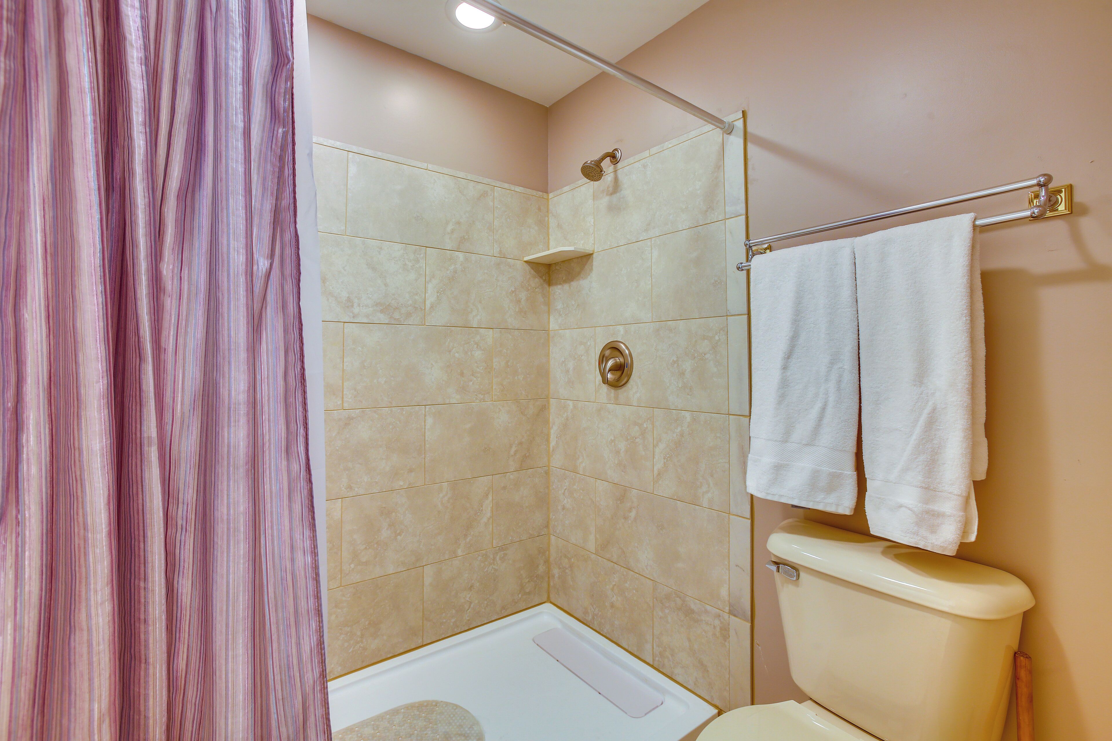 A bathroom with a shower, toilet, and a towel rack.