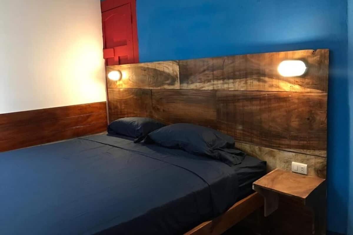 A single bed with a wooden headboard, two bedside lamps, and a power outlet on the nightstand.