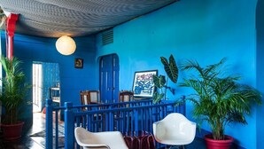 A room with blue walls, a red door, and a ceiling with a patterned design. There are two white chairs and a table with a red tablecloth. - Hotel Estrella San Juan Del Sur (San Juan del Sur)
