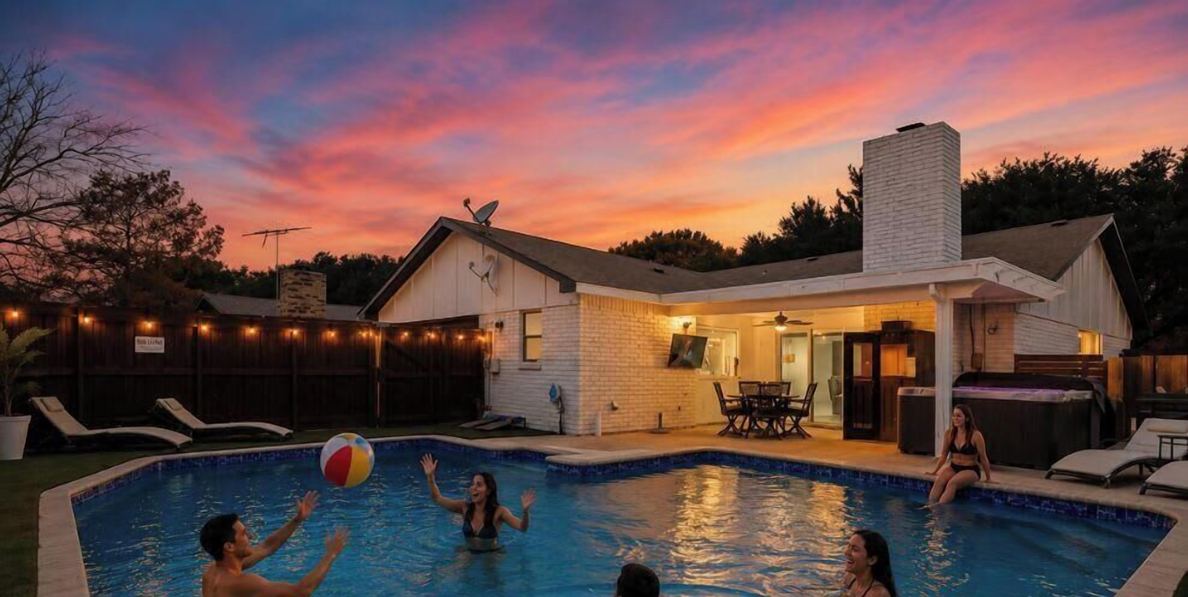 Une piscine avec une maison en arrière-plan, un espace patio et un ciel au coucher du soleil.