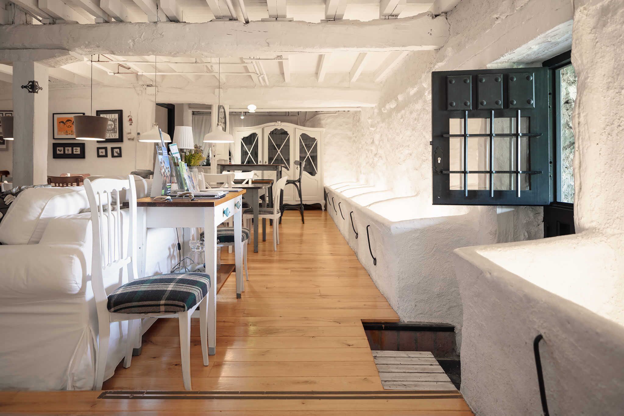 A spacious room with a wooden floor, white furniture, and a large window with a view.