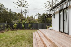 A modern house with a wooden deck, a black fence, and a variety of plants. - The Lull Culburra (Culburra Beach)