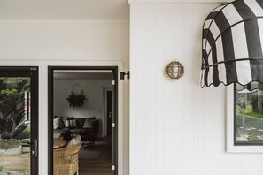 A room with a large window, a black and white striped awning, and a wall-mounted light fixture. - The Lull Culburra (Culburra Beach)